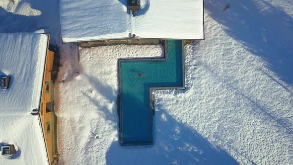 Aerial drone view of a woman swimming in a pool at a luxury spa resort