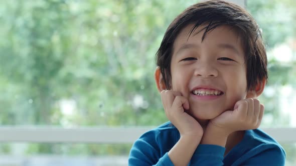 Cute Asian Child Resting Chins On Hands On Wood Table