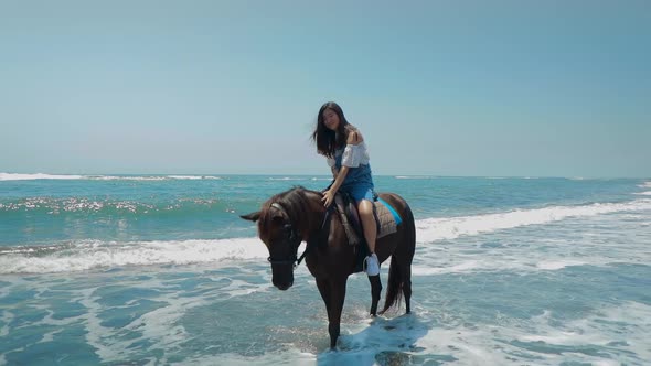 Cute Chinese Teenager Rides a Horse On The Beach In Bali