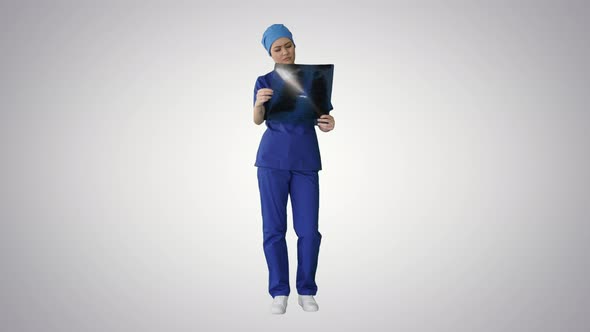 Thinking Female Doctor in Uniform Examining a Chest Xray on Gradient Background