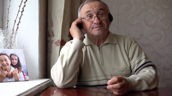 Smiling Senior Man Wear Earphones Wave to Camera Having Video Call on Laptop Happy Elderly Male in