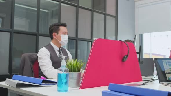 Asian young businessman and woman working on laptop computer in office with new normal lifestyle.