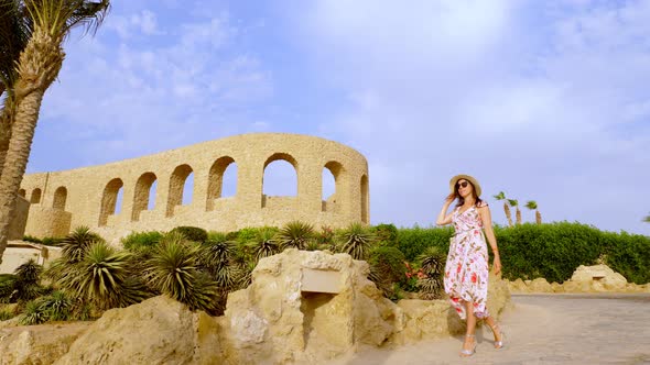 Smiling, Beautiful Young Woman, in Sunglasses, Light Summer Dress, Fluttering in Wind, and Sun Hat