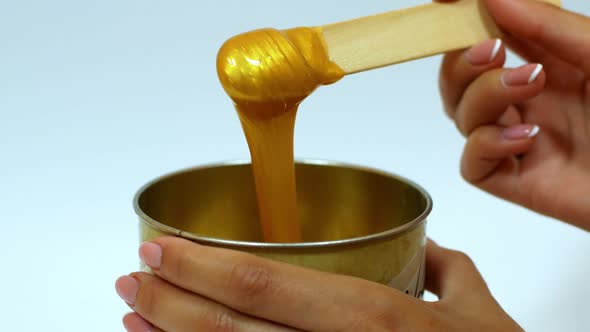 Depilatory wax Master mixes the golden-colored wax. Removing unwanted hair with wax.