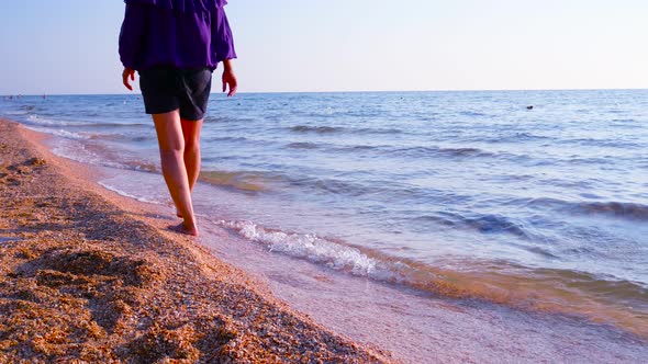 A Girl Walks Along the Coast Along the Edge of the Sea