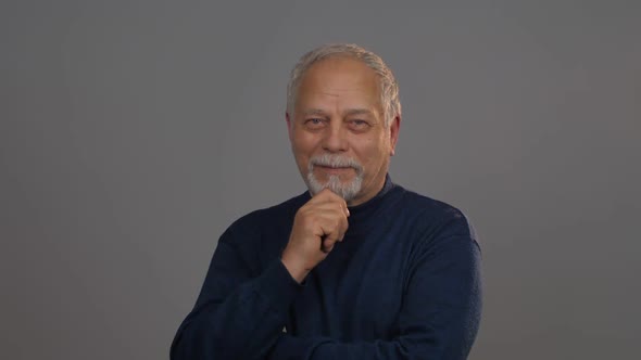 Thoughtful Man Looks Straight Holding Hand on Beard