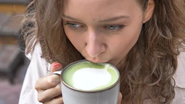 Woman with Fair Hair Drinks Capuccino From Porcelain Cup