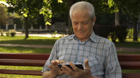 Senior Man Uses Tablet on the Bench