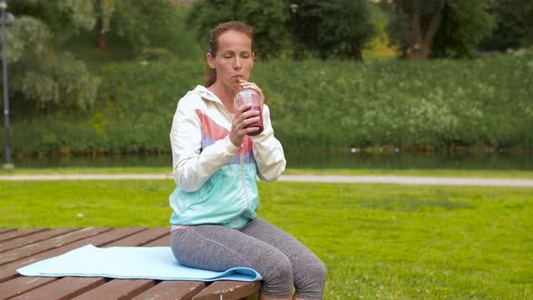 Woman Drinking Smoothie After Exercising in Park 