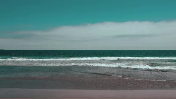 Aerial moving towards the waves at the beach