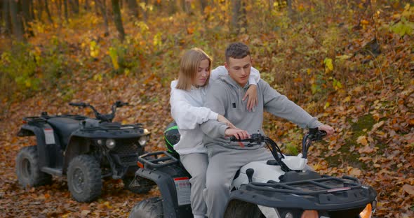 A Young Couple Rides an ATV Offroad in the Autumn Forest