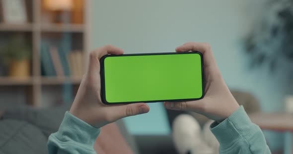 Man Holding Green Screen Mobile in Horizontal Position