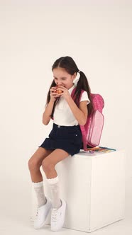 Cheerful Girl with Backpack Sitting in Studio