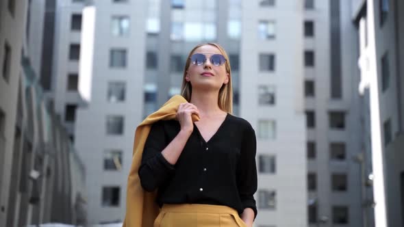 Bottom view, pretty blonde in sunglasses walks down the street