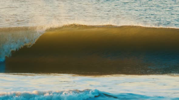 Ocean Wave Breaks on the Shore During Sunrise