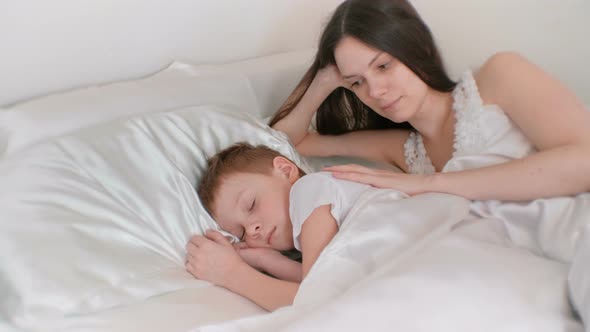 Mom Puts Her Son To Bed. Stroking His Back and Kissing