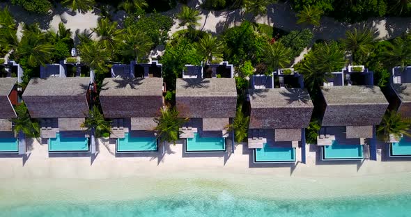 Daytime aerial abstract shot of a sandy white paradise beach and blue sea background in 4K