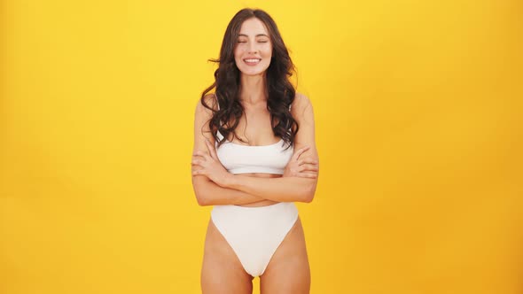 A pleased brunette woman wearing swimsuit nodding