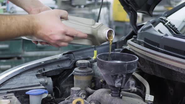 Car Maintenance Servicing Mechanic Pouring New Oil Lubricant Into the Car Engine. Pouring Fresh New