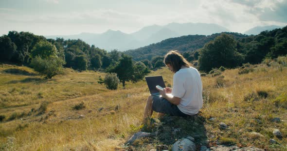 Creative Freelance Worker Using Laptop Computer and Smartphone on Summer Journey