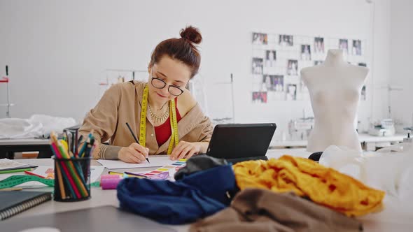 Young Professional Lady Tailor Wearing Eyeglasses Sketching New Clothes Collection Researching