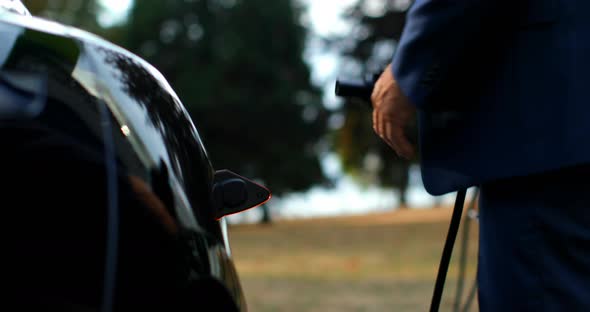 Businessman charging electric car at charging station 4k