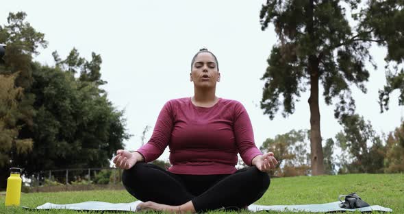 Young curvy woman doing yoga exercises outdoor