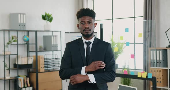 Businessman in Suit Posing on Camera with Crossed Arms in Modern Office Room at Daytime