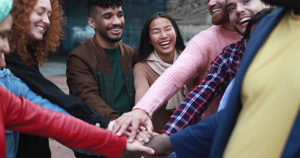 Group of happy young people stacking hands outdoor