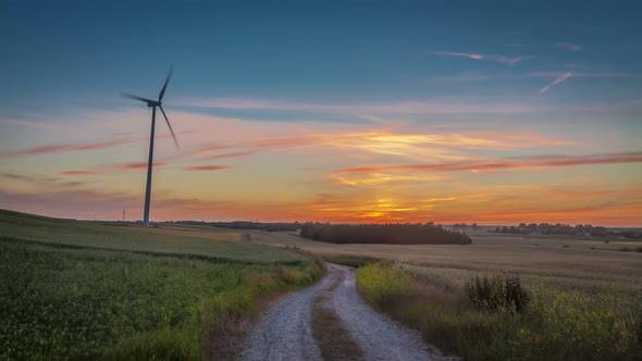 Beautiful sunset over a field with a windmill and country road, timelapse, 4K