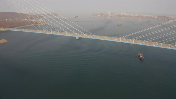 Drone View of a Modern Corvetteclass Ship Going Out to Sea Under the Bridge