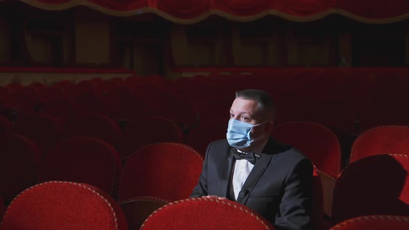 Sad man in medical mask in empty theater. 