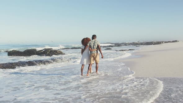 African American couple walking seaside