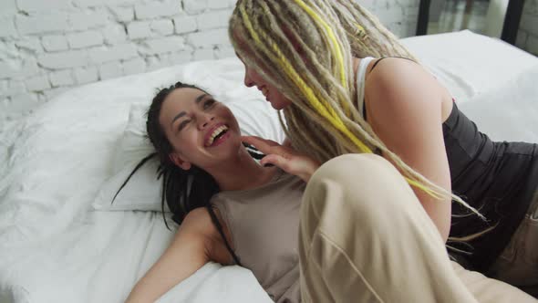 Couple Talking and Laughing in a Comfortable Bed Near White Wall