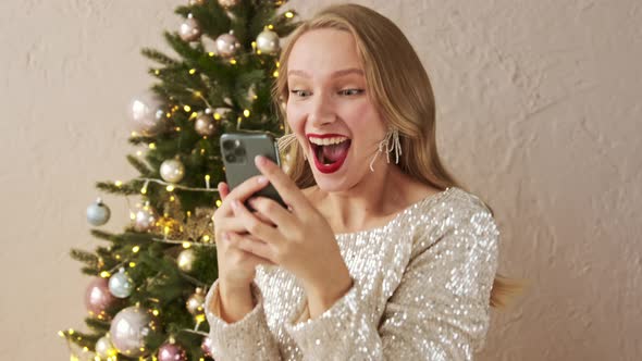 Amazed lucky christmas woman using mobile phone looks and sees the message with a good news.