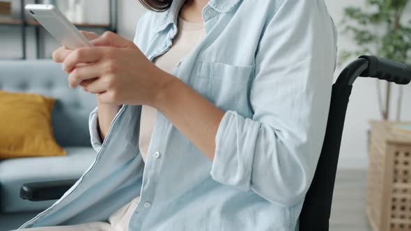 Slow Motion of Attractive Young Lady in Wheelchair Using Smartphone Texting Smiling at Home