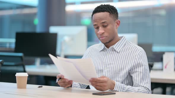 African Businessman Reading Documents in Office