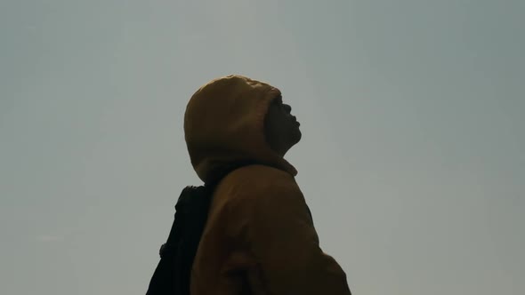 Silhouette of woman closed her eyes, praying on top of a mountain during sunset.