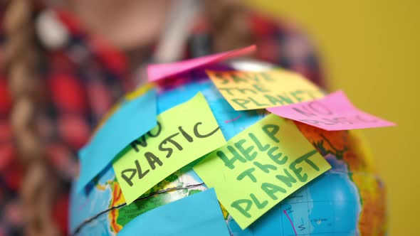 Closeup Adhesive Notes Calling Ecological Conservation on Earth Globe in Hands of Unrecognizable