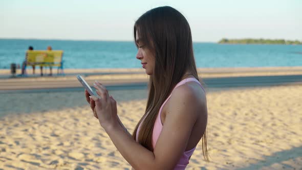 Sporty Young Woman Using Mobile Phone at Stadium