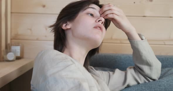 Unhappy Young Woman Sitting on the Couch and Look for a Solution of Problem