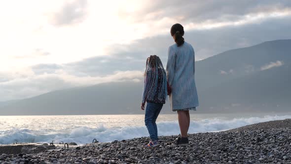 Little Girl with Mother Watching Sunset By a Sea