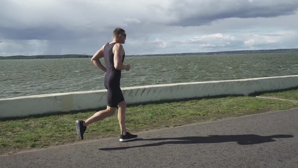 Prol Runner Runs on a Road Near the Lake Athlete Trains in on a Sunny Day Running Before Triathlon