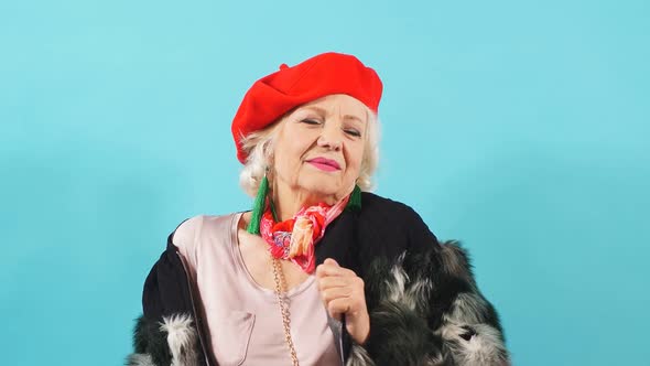 Smiling Cheerful Older Lady Dances and Looks at the Camera. Isolated Yellow Background.