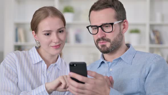 Portrait of Serious Young Couple Using Smartphone 