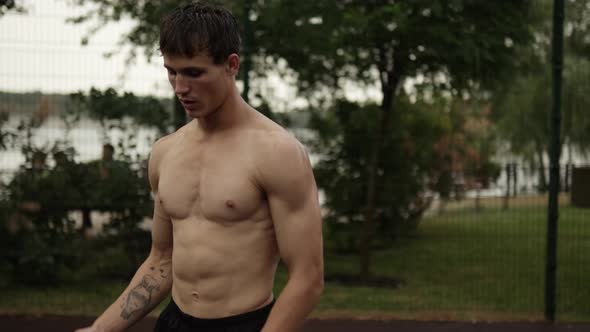 A muscular guy is playing basketball while training