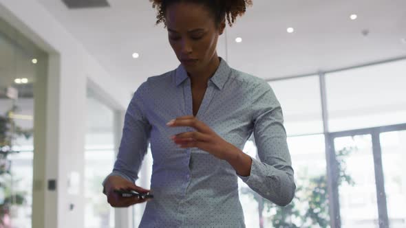 Mixed race businesswoman taking photos with smartphone in office