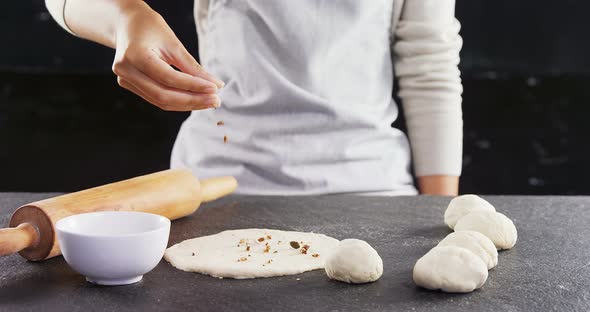 Woman adding dry fruits over flattened dough 4k