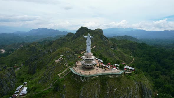 Aerial of a Jesus Christ Statue in Tana Toraja Sulawesi at the top of a mountain with tourists and s