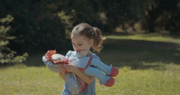 Cute little girl wearing a blue dress playing alone outdoors